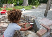 Buiten op kinderdagverblijf ’t Schommeltje spelen de kinderen in de natuurlijke buitenruimte / SKRS